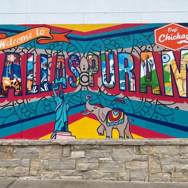 Colorful mural with "Welcome to Dallaspuram" text, Statue of Liberty, and an elephant.