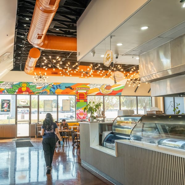 A vibrant Desi Chichas Indian restaurant interior with colorful murals, modern lighting, and a dessert counter.
